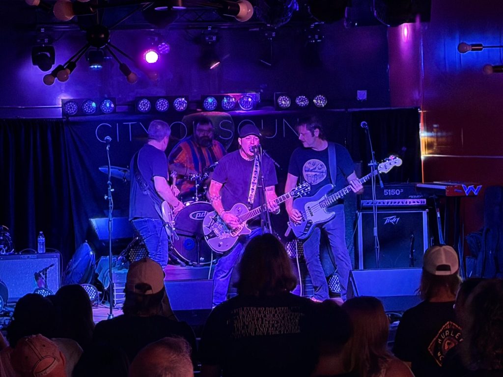 Band on stage under purple lights at Feedback Music Lounge